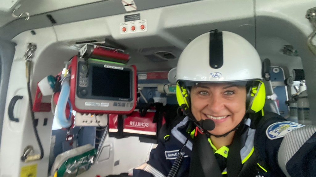 Notärztin mit Helm und Headset lächelt im Inneren eines Rettungshubschraubers